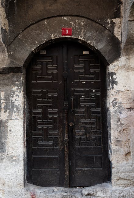 A dark historic door with a red plate number 3 signifying stability